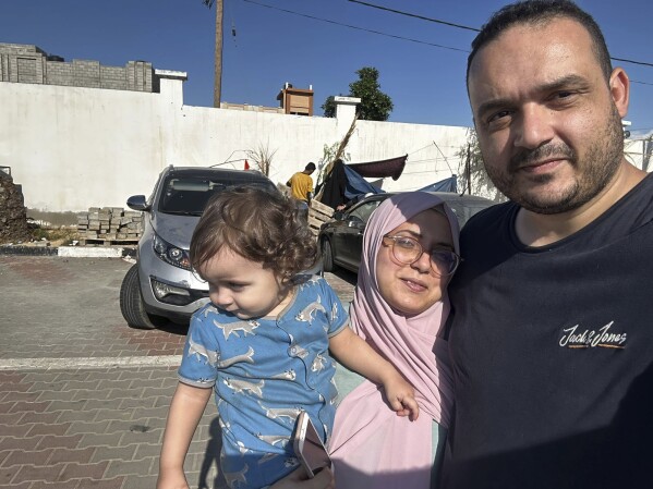 This photo provided by Hosein Owda dated Sunday, Oct. 15, 2023 shows him with his wife, Wafa, and 1-year-old son Zein at the shelter in Khan Younis. The Owda family had arrived two days earlier to the shelter after they lost their apartment. They are now among 22,000 people sheltering at a UN center in Khan Younis, miles away from their home in Gaza city. (Hosein Owda via AP)