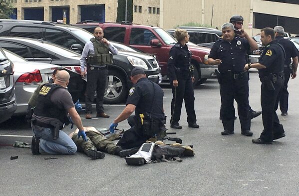 Law enforcement officers attend to an injured shooter in a parking lot after he fired shots at the Earle Cabell Federal Building in downtown Dallas, Monday, June 17, 2019. (Tom Fox/The Dallas Morning News) MANDATORY CREDIT, NO SALES, MAGS OUT,  TV OUT, INTERNET USE BY AP MEMBERS ONLY