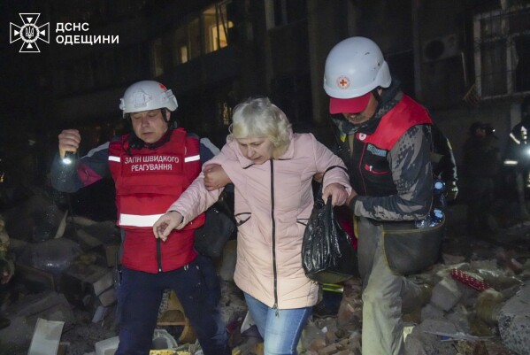In this photo provided by the Ukrainian Emergency Service, rescuers help evacuate an elderly resident from her damaged house following Russia's air raid in Odesa, Ukraine, Thursday, May 1, 2025. (Ukrainian Emergency Service via AP)