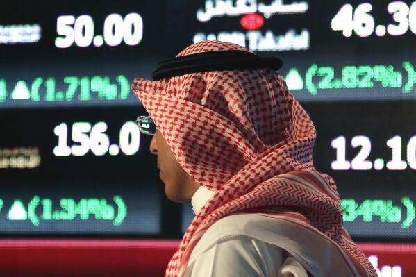 FILE - In this June 15, 2015, file photo, a Saudi man walks through the Tadawul Saudi Stock Exchange in the Saudi Arabian capital, Riyadh. Saudi Arabia's key stock market suspended trading Wednesday, June 2, 2021, over what it referred to as a technical glitch, without elaborating. (AP Photo/Hasan Jamali, File)