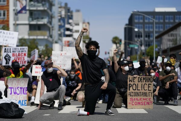Demonstrators kneel in a moment of silence outside the Long Beach Police Department on Sunday, May 31, 2020, in Long Beach during a protest over the death of George Floyd. Protests were held in U.S. cities over the death of Floyd, a black man who died after being restrained by Minneapolis police officers on May 25. (AP Photo/Ashley Landis)