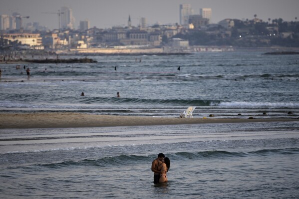 People bathe in the Mediterranean Sea along the beachfront in Tel Aviv, Israel, on Saturday, June 14, 2025. (AP Photo/Ohad Zwigenberg)