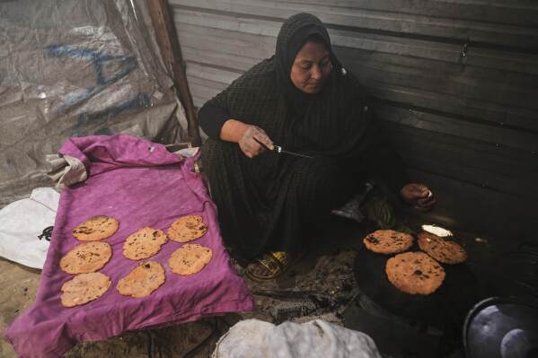 Nevin Qassim, a displaced Palestinian woman, prepares ground lentil dough as a substitute for bread due to a shortage of flour in the Gaza Strip, in Khan Younis, on Sunday, May 11, 2025. (AP Photo/Abdel Karem Hanna)