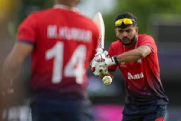 United States' Milind Kumar throws the ball to teammate Monank Patel as they warm up ahead the men's T20 World Cup cricket match between the United States and Canada at Grand Prairie Stadium, in Grand Prairie, Texas, Saturday, June 1, 2024. (AP Photo/Julio Cortez)