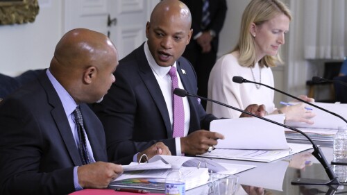 Maryland Gov. Wes Moore, center, talks to Treasurer Dereck Davis during a meeting of the Board of Public Works, which approved $2.9 million in compensation, Wednesday, July 5, 2023 in Annapolis, Md., for John Huffington, who was wrongly imprisoned for 32 years, including a decade spent on death row, for two murders he did not commit. Comptroller Brooke Lierman, who is a board member with Moore and Davis, is seated right. (AP Photo/Brian Witte)