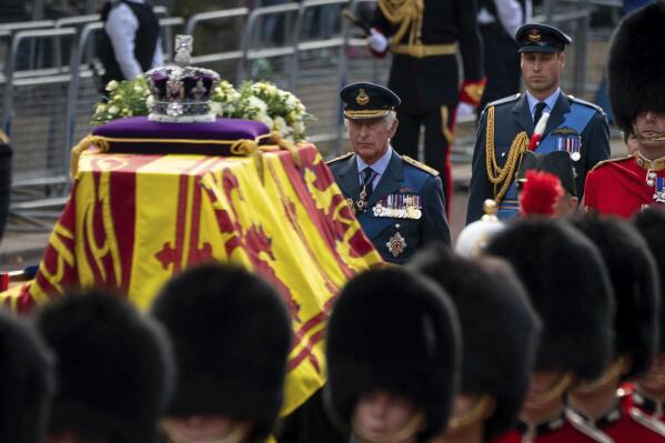 Britain's King Charles III and Prince William follow the coffin of Queen Elizabeth II, draped in the Royal Standard with the Imperial State Crown placed on top, carried on a horse-drawn gun carriage of the King's Troop Royal Horse Artillery, during the ceremonial procession from Buckingham Palace to Westminster Hall, London, Wednesday Sept. 14, 2022. The Queen will lie in state in Westminster Hall for four full days before her funeral on Monday Sept. 19. (Aaron Chown/Pool via AP)
