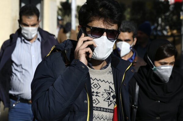 FILE — In this Monday, March 2, 2020 file photo, a man wearing a face mask, to help protect against the new coronavirus, speaks on his cellphone in downtown Tehran, Iran. Local media reported Thursday, March 26, 2020, that nearly 300 people have been killed and more than 1,000 sickened by ingesting toxic methanol across the Islamic Republic out of the false belief it kills the new coronavirus. That's as messages forwarded through social media on people surviving the virus by drinking whiskey and using alcohol-based hand sanitizer somehow saw people seek out bootleg liquor in Iran. (AP Photo Vahid Salemi, File)