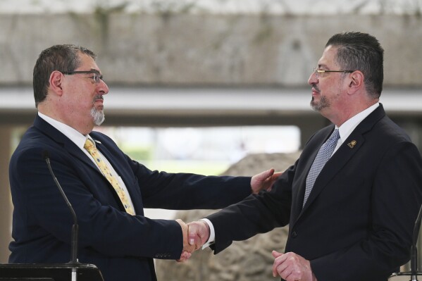 Guatemalan President-elect Bernardo Arévalo, left, and Costa Rica's President Rodrigo Chaves, shake hands during a welcoming ceremony in San Jose, Costa Rica, Wednesday, Dec. 13, 2023. Chaves received Arévalo Wednesday as the visiting politician tries to face down prosecutors’ attempts at home to derail his inauguration in barely a month’s time. (AP Photo/Carlos Gonzalez)