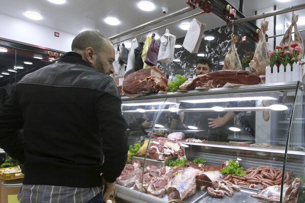 People shop for beef at a butchery in Algiers, Algeria, Sunday, Feb. 18, 2024. Algeria is importing massive amounts of beef and lamb to confront an explosion in demand for meat expected throughout the Muslim holy month of Ramadan, hoping to stabilize prices as the country's economy continues to struggle. The oil-rich North African nation is among countries working to import food and fuel, hoping to meet the requirements of Algerians preparing nightly feasts as their families break their sunrise-to-sunset fasts. (AP Photo/Fateh Guidoum)