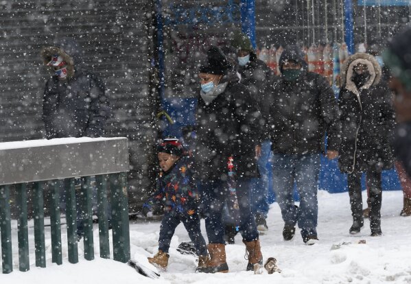 A girl and her mother walk through a snowstorm, Thursday, Dec. 17, 2020 in the Bronx borough of New York. (AP Photo/Mark Lennihan)