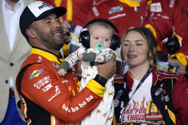 Bubba Wallace , left, celebrates in Victory lane with his son Becks Hayden and his wife Amanda Carter after winning the first of two NASCAR Daytona 500 qualifying auto races at Daytona International Speedway, Thursday, Feb. 13, 2025, in Daytona Beach, Fla. (AP Photo/John Raoux)