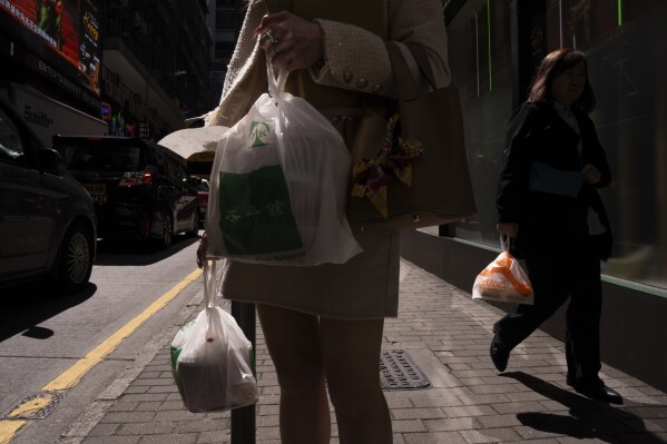 Pedestrians carry takeaway food plastic bags in Hong Kong, Wednesday, March 13, 2024. Hong Kong has long been a major producer and consumer of great food, and a great amount of plastic and Styrofoam to go with it. That’s going to change as new legislation aiming to stop the sale and distribution of Styrofoam products and single-use plastic cutlery went into effect on Monday, April 22, 2024. (AP Photo/Louise Delmotte)