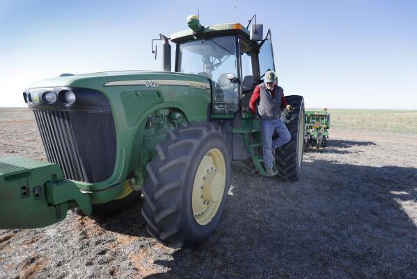 Tim Black climbs down from his tractor that he's using to sow grass on his Muleshoe, Texas, farm on Monday, April 19, 2021. The longtime corn farmer now raises cattle and plants some of his pasture in wheat and native grasses because the Ogallala Aquifer, needed to irrigate crops, is drying up. (AP Photo/Mark Rogers)