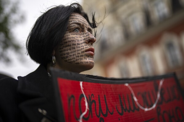 A woman dons tally marks on her face representing the number of days prisoners of war who defended Mariupol have been held in Russia, during a rally in Kyiv, Ukraine, April 21, 2024. (AP Photo/Francisco Seco)