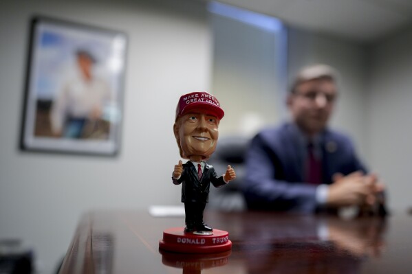 A bobblehead of Republican presidential nominee former President Donald Trump sits on the desk as Speaker of the House Mike Johnson, R-La., speaks during an interview with The Associated Press at the Lucas County Republican Party headquarters in Holland, Ohio, Saturday, Oct. 26, 2024. (AP Photo/Carolyn Kaster)