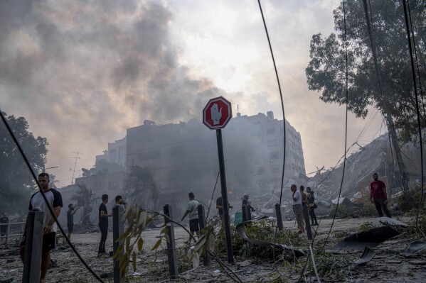 Palestinians inspect the rubble of a building after it was struck by an Israeli airstrike, in Gaza City, Sunday, Oct. 8, 2023. (AP Photo/Fatima Shbair)