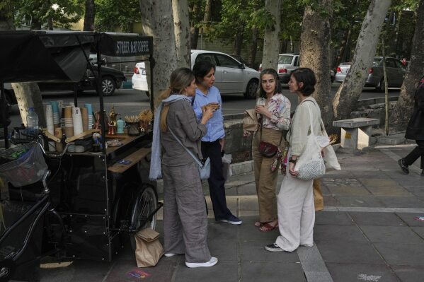 Iranian women drink coffee on the sidewalk in northern Tehran, Iran, Saturday, May 3, 2025. (AP Photo/Vahid Salemi)