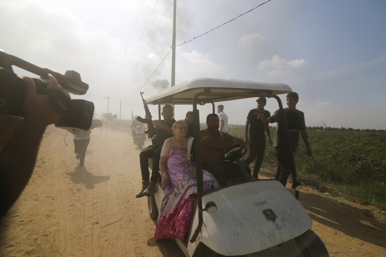 FILE - Palestinians transport their hostage, Yaffa Adar, an 85-year-old Israeli great-grandmother and Holocaust survivor, from her home in Kibbutz Nir Oz into the Gaza Strip on Oct. 7, 2023. An Associated Press review of hundreds of messages shared among Nir Oz residents, security camera footage and Hamas instruction manuals show the group planned ahead of time to target civilians, a change in tactic that heavily impacted how the war in Gaza played out. (AP Photo, File)