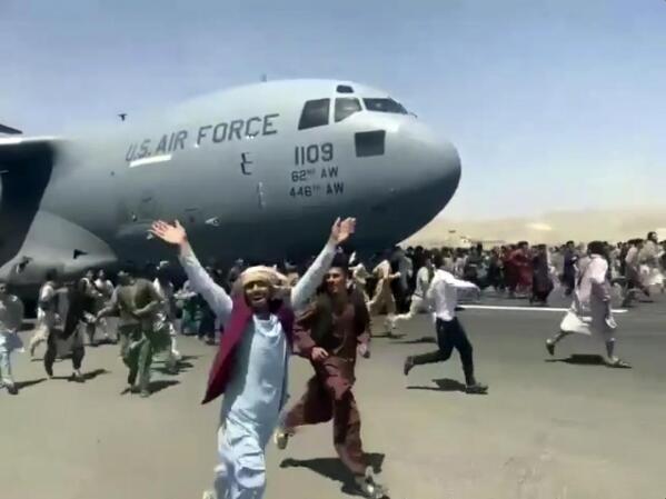 Hundreds of people run alongside a U.S. Air Force C-17 transport plane as it moves down a runway  of the international airport, in Kabul, Afghanistan, Monday, Aug.16. 2021. Thousands of Afghans have rushed onto the tarmac of Kabul’s international airport, some so desperate to escape the Taliban capture of their country that they held onto an American military jet as it took off and plunged to death. (Verified UGC via AP)