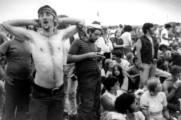 FILE - Music fans relax during a break in the entertainment at the Woodstock Music and Arts Fair, Aug. 16, 1969, in Bethel, N.Y. An estimated 450,000 people attended the Woodstock festival in August 1969, and most of that crowd was composed of teenagers or young adults now in the twilight of their lives. That ticking clock is why the Museum at Bethel Woods, based at the site of the festival, is immersed in a five-year project traveling around the United States recording the oral histories of people were there, preserving the Woodstock memories before they fade away. (AP Photo, File)