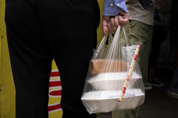 A pedestrian carries takeaway food plastic bag in Hong Kong, Thursday, Feb. 21, 2024. Hong Kong has long been a major producer and consumer of great food, and a great amount of plastic and Styrofoam to go with it. That’s going to change as new legislation aiming to stop the sale and distribution of Styrofoam products and single-use plastic cutlery went into effect on Monday, April 22, 2024.(AP Photo/Louise Delmotte)