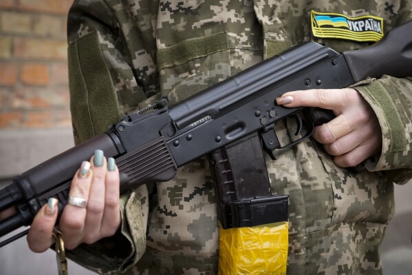 FILE - An armed civil defense woman holds a Kalashnikov assault rifle while patrolling an empty street due to a curfew in Kyiv, Ukraine, Feb. 27, 2022. The U.S. has transferred to Ukraine 1.1 million rounds of small arms ammunition that it seized from Iran, U.S. Central Command said Wednesday. (AP Photo/Efrem Lukatsky, File)