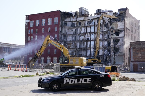 FILE - A police officer sits parked at the site of a building collapse at the start of demolition, Monday, June 12, 2023, in Davenport, Iowa. The owner of the apartment building that collapsed in May, killing three people, has filed a lawsuit that blames an engineering company for not warning the building was structurally unsound and that residents should be evacuated. (AP Photo/Charlie Neibergall, File)