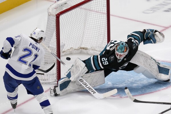 Tampa Bay Lightning center Brayden Point, left, scores a goal against San Jose Sharks goaltender Mackenzie Blackwood during the third period of an NHL hockey game Thursday, March 21, 2024, in San Jose, Calif. (AP Photo/Godofredo A. Vásquez)