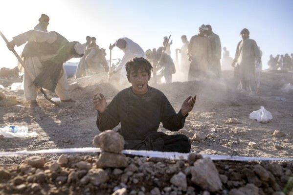 An Afghan boy mourns next to the grave of his little brother who died due to an earthquake, in Zenda Jan district in Herat province, western of Afghanistan, Monday, Oct. 9, 2023. Saturday's deadly earthquake killed and injured thousands when it leveled an untold number of homes in Herat province. (AP Photo/Ebrahim Noroozi)