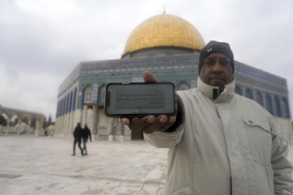 A worshipper stands in the Al-Aqsa Mosque compound in the Old City of Jerusalem, Jan. 29, 2022, and holds his mobile phone showing a threatening message. The May 2021 text, signed ”Israeli intelligence,” reads: "Hello! You have been spotted as having participated in acts of violence in Al-Aqsa Mosque, and we will hold you accountable." (AP Photo/Mahmoud Illean)