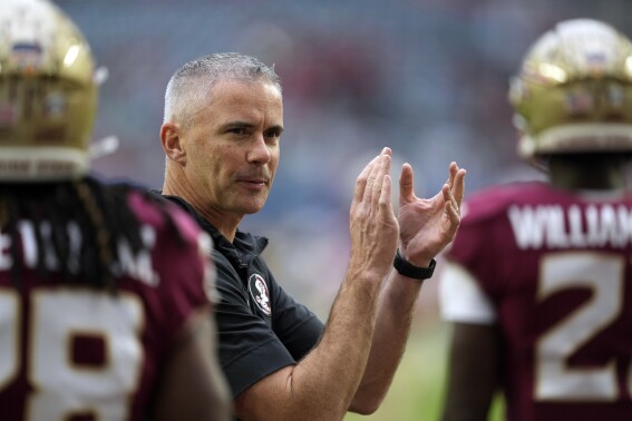 FILE - Florida State head coach Mike Norvell claps as his players warm up for the Orange Bowl NCAA college football game against Georgia, Saturday, Dec. 30, 2023, in Miami Gardens, Fla. Norvell, like most every other team in the Atlantic Coast Conference, has spent the spring handling change. He hopes it can lead to another league title and a spot in the 12-team College Football Playoff. (AP Photo/Rebecca Blackwell, File)
