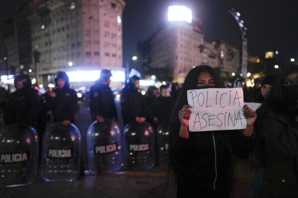 A demonstrator holds a sign that reads in Spanish "Killer police" during a protest in Buenos Aires, Argentina, Thursday, Aug. 10, 2023. The original protest which had been called by several left-wing groups, intensified after police tried to disperse it and a man died of a heart attack while police were detaining him. (AP Photo/Natacha Pisarenko)