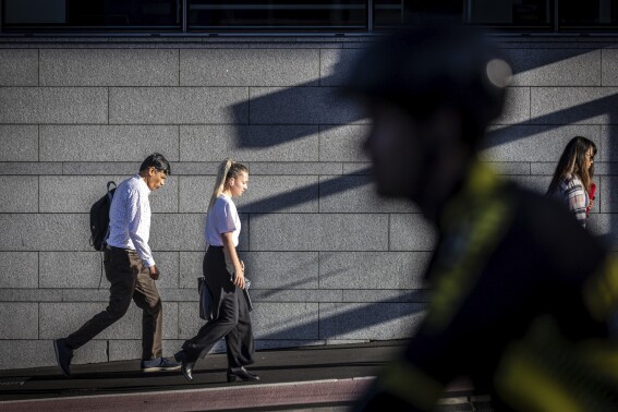 Commuters walk in the early morning summer sun in Auckland, New Zealand, Wednesday, Feb. 14, 2024. New Zealand has entered its second recession in 18 months after the latest round of GDP figures confirmed its economy contracted in the last quarter of 2023. The country's economy shrank by 0.1% in the quarter to December, and 0.7% in per capita terms, the New Zealand's official statistics agency, Stats NZ, announced on Thursday, March 21. (Michael Craig/New Zealand Herald via AP)