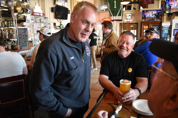 FILE - Montana U.S. House candidate and former Secretary of Interior Ryan Zinke, left, speaks with patrons at Metals Sports Bar and Grill, May 13, 2022, in Butte, Mont. Zinke is seeking election to a newly created U.S. House district. (AP Photo/Matthew Brown, File)