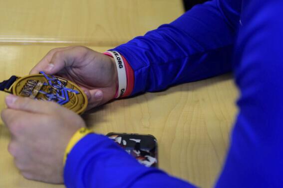 Spring Grove wrestler Logan Herbst holds Helen Maroulis' gold medal during a meeting with the Olympian at Spring Grove Area High School in Jackson Township, York County, Pa., Monday, Oct. 18, 2021. (Matt Allibone/York Daily Record via AP)
