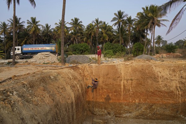 A laborer climbs out after digging a temporary pond which will be used to store groundwater later to be sold at high costs to offices and apartments, in Bengaluru, India, Monday, March 11, 2024. (AP Photo/Aijaz Rahi)