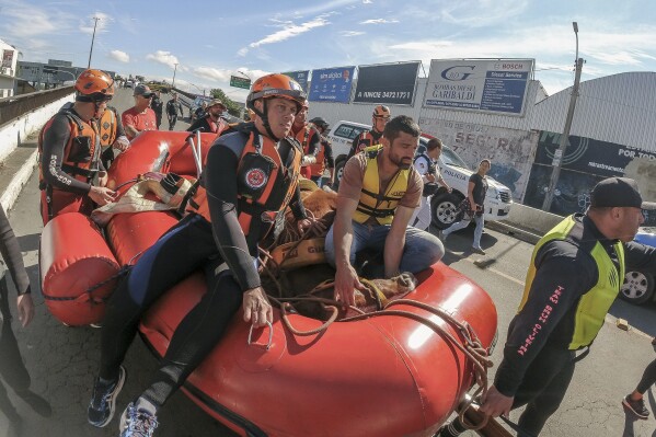 Bombeiros usam jangada para transportar cavalo após ele ter sido resgatado do telhado, onde ficou dias preso nas enchentes, após fortes chuvas em Canoas, Rio Grande do Sul, Brasil, quinta-feira, 9 de maio de 2024. (AP Photo / Wesley Santos)