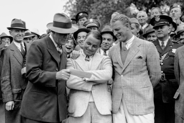 In this April 8, 1935, file photo, golfer Gene Sarazen, center, receives a check for $1,500 from sportswriter Grantland Rice, left, for winning the Augusta National Invitation Tournament in Augusta, Ga. (AP Photo/File)