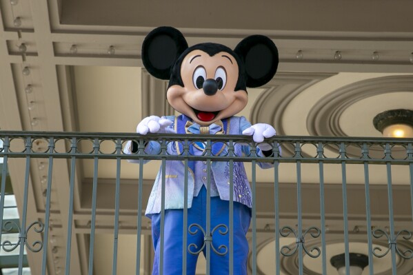 FILE - An actor dressed as Mickey Mouse greets visitors at the entrance to Magic Kingdom Park at Walt Disney World Resort, April 18, 2022, in Lake Buena Vista, Fla. The earliest version of Disney's most famous character, Mickey Mouse, and arguably the most iconic character in American pop culture, will become public domain on Jan. 1, 2024. (AP Photo/Ted Shaffrey, File)