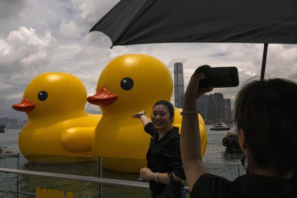 Members of the public photograph an art installation called "Double Ducks" by Dutch artist Florentijn Hofman at Victoria Harbour in Hong Kong, Friday, June 9, 2023. Two giant inflatable ducks made a splash in Hong Kong's Victoria Harbor on Friday, marking the return of a pop-art project that sparked a frenzy in the city a decade ago. (AP Photo/Louise Delmotte)