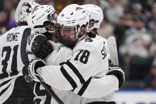 Western Michigan's Wyatt Schingoethe (18) and teammate Tristan Lemyre celebrate a double overtime victory over Denver in a semifinal game in the NCAA Frozen Four men's college hockey tournament, Thursday, April 10, 2025, in St. Louis (AP Photo/Jeff Roberson)