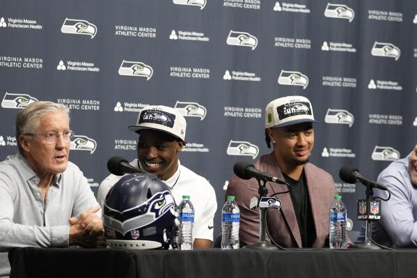 From left to right, Seattle Seahawks head coach Pete Carroll speaks as first-round NFL football draft picks Devon Witherspoon, a cornerback from Illinois, and Jaxon Smith-Njigba, a wide receiver from Ohio State, along with general manager John Schneider, listen during a news conference, Friday, April 28, 2023, at the team's headquarters in Renton, Wash. (AP Photo/Lindsey Wasson)