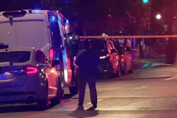 In this image taken from video provided by WJLA, a bystander watches as law enforcement works the scene after two staff members of the Israeli embassy in Washington were shot and killed outside the Capital Jewish Museum on Wednesday, May 21, 2025, in Washington. (WJLA via AP)