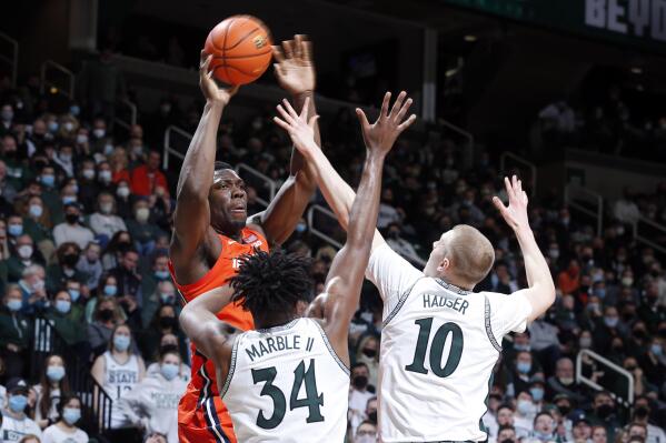 Illinois' Kofi Cockburn, left, passes against pressure from Michigan State's Joey Hauser, right, and Julius Marble (34) during the first half of an NCAA college basketball game, Saturday, Feb. 19, 2022, in East Lansing, Mich. (AP Photo/Al Goldis)