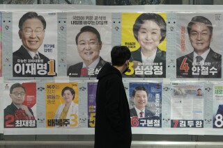 A man watches posters of presidential candidates on a street in Seoul, South Korea, March 3, 2022.  (AP Photo/Ahn Young-joon)
