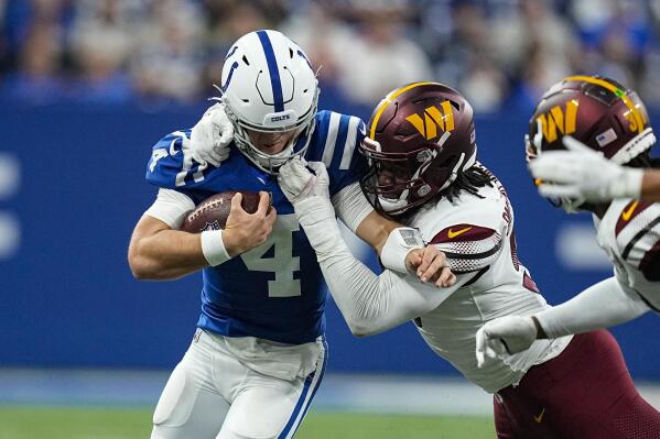 Indianapolis Colts quarterback Sam Ehlinger (4) is tackled by Washington Commanders defensive end James Smith-Williams (96) in the first half of an NFL football game in Indianapolis, Sunday, Oct. 30, 2022. (AP Photo/Darron Cummings)