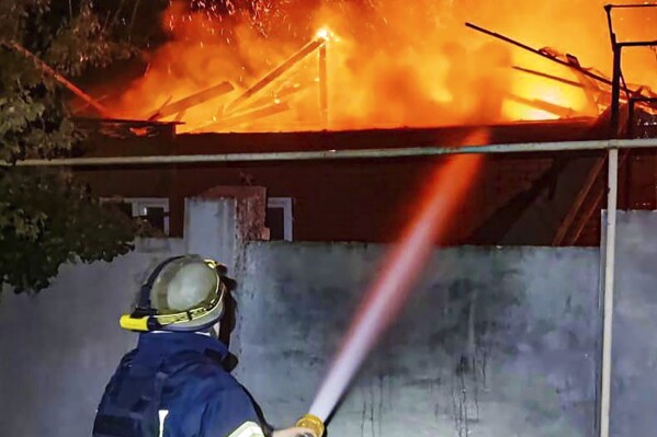 In this photo provided by the Ukrainian Emergency Service, emergency services personnel work to extinguish a fire in Kherson, Ukraine, on Monday, Oct. 30, 2023, following Russian shelling attacks. Russian shells struck residential areas of Ukraine's southern Kherson region, killing a 91-year-old woman in what a local official described Monday as a 