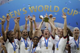 FILE - In this July 7, 2019, file photo,  United States' Megan Rapinoe lifts up a trophy after winning the Women's World Cup final soccer match between US and The Netherlands at the Stade de Lyon in Decines, outside Lyon, France. The  global players' association released its report on the state of  women's soccer, after warning that the coronavirus  outbreak could have a disastrous impact following the gains of last summer's Women's World Cup.  (AP Photo/Alessandra Tarantino, File)