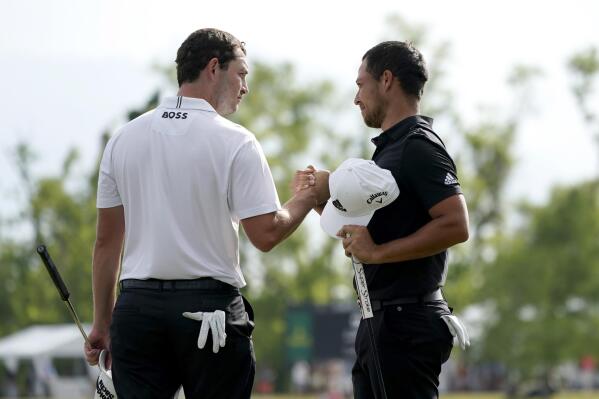 Patrick Cantlay, left, and his teammate Xander Schauffele, right, congratulate each other after their win in the PGA Zurich Classic golf tournament at TPC Louisiana in Avondale, La., Sunday, April 24, 2022. (AP Photo/Gerald Herbert)