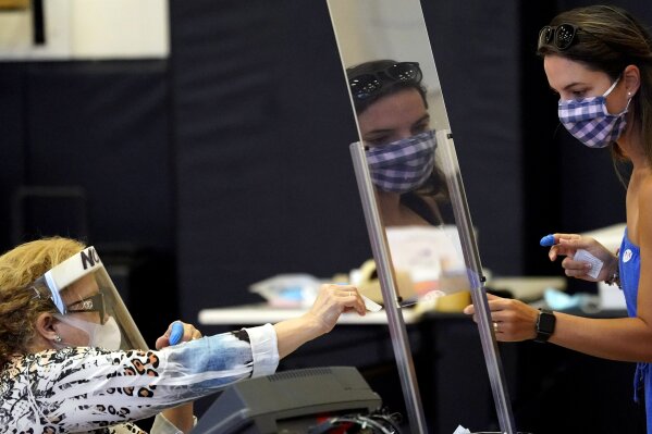 FILE - In this June 29, file photo, Harris County election clerk Nora Martinez, left, helps a voter, in Houston. Republican efforts to restrict voting access are taking shape in statehouses across the country with a flurry of legislation aimed at limiting measures that led to record turnout in the 2020 presidential election. (AP Photo/David J. Phillip, File)